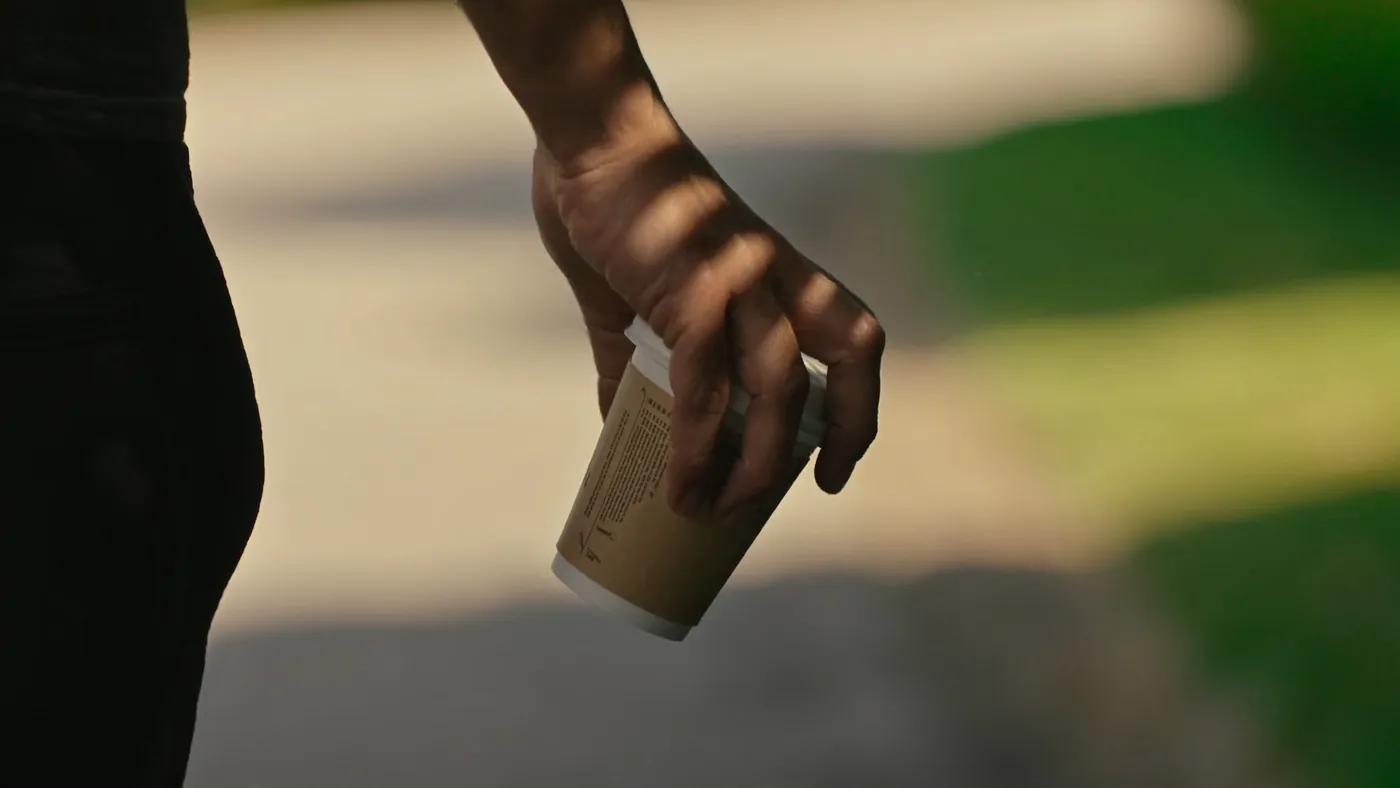 A hand carrying a cup on a morning walk