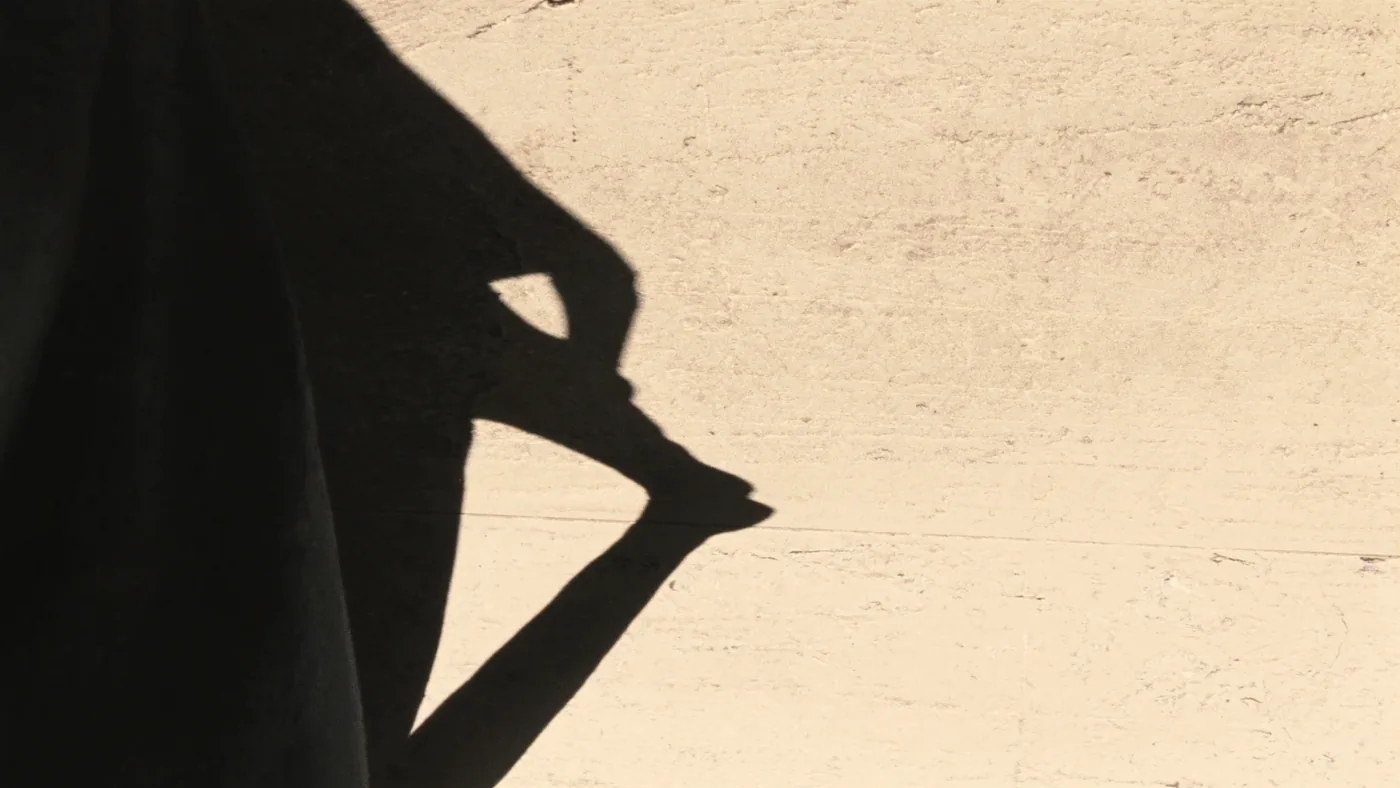 A figure's shadow across bare concrete