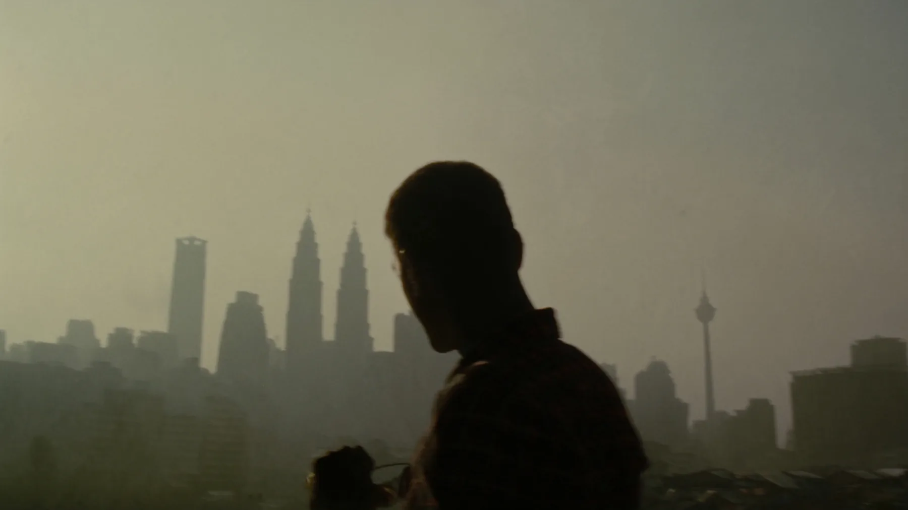 A figure silhouetted against the Kuala Lumpur skyline at dusk